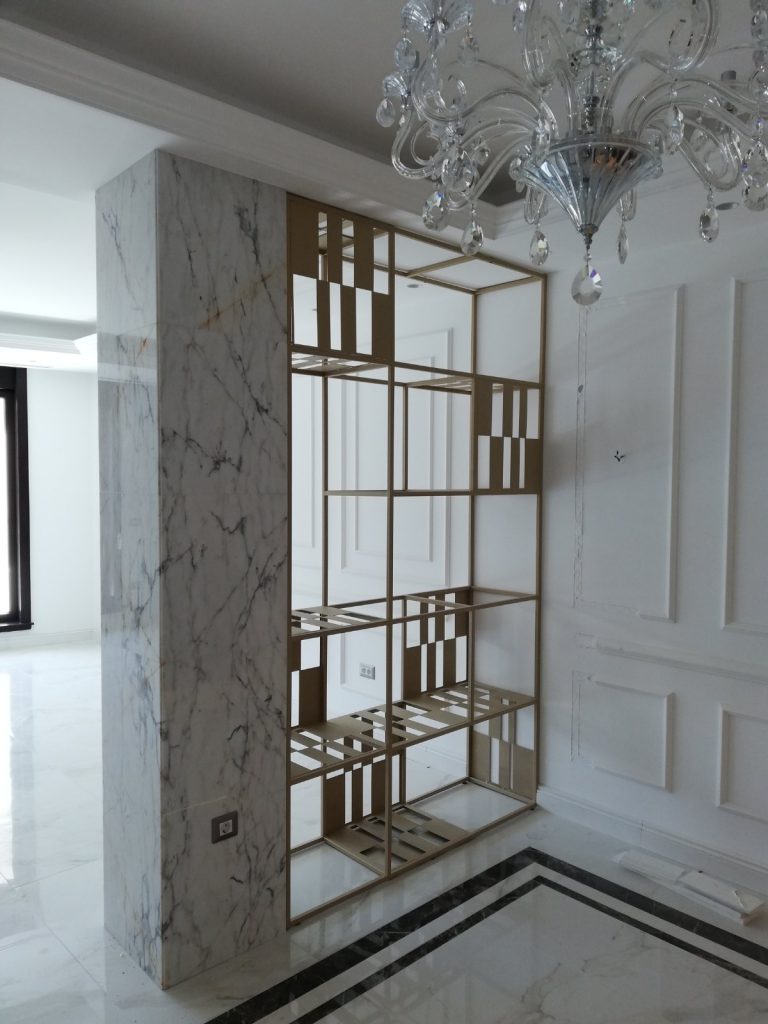 A gold shelf in a modern apartment surrounded by marble